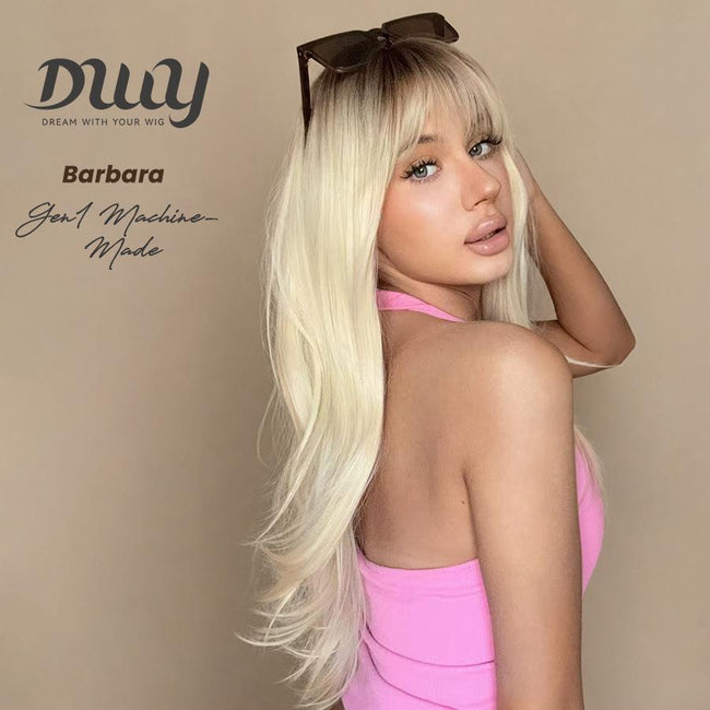 DWY Barbara machine-made wig with long, wavy blonde hair and curtain bangs, dark roots, modeled by a woman in a pink top.