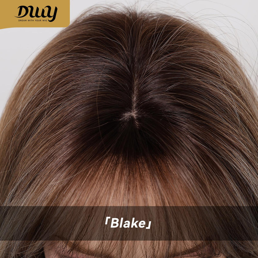 A detailed close-up view of the parting line and roots of a DWY brand synthetic wig, showing a realistic scalp effect. The hair is a multi-tonal brown with subtle highlights and features a straight fringe. The gold DWY logo is visible at the top left, and the product name 「Blake」 is at the bottom.