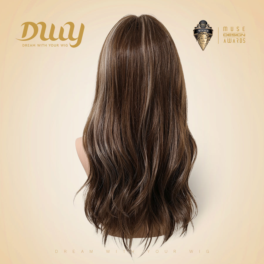A back view of a mannequin head displaying a long, wavy brown wig with subtle highlights. The DWY brand logo is in the upper left, and a Muse Design Awards winner logo is in the upper right. The background is a soft, light beige studio setting.