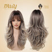 A double-view product shot showing both the front and back of a DWY long, layered synthetic wig with bangs in highlighted brown and blonde, against a beige background with brand logo.