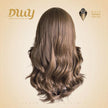 A back view of the medium-brown wavy hair wig on a mannequin head. It shows the hair length and texture from behind. The DWY Dream With Your Wig logo and a Muse Design Awards badge are in the upper-left and right corners, respectively.