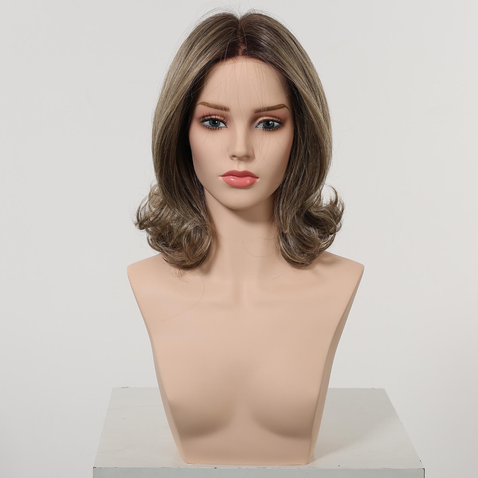 A front view of a realistic female mannequin head displaying a DWY wig. The medium-length, layered synthetic hair is a mix of dark brown and lighter ash brown highlights, styled with soft, flipped-out curls at the ends. A monofilament part is visible. The mannequin has neutral makeup. The background is a clean, plain studio white.