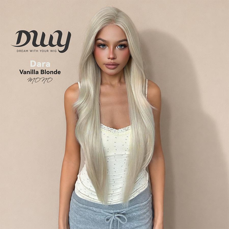A woman models the DWY 'Dara' wig in a 'Vanilla Blonde' shade, featuring a monofilament part. This long, straight, light blonde hairpiece has subtle layering and a natural appearance. The model wears a cream lace-trimmed tank top and grey sweatpants. The background is a simple, solid beige wall with text overlay. There is a blue button on the chest of the model.